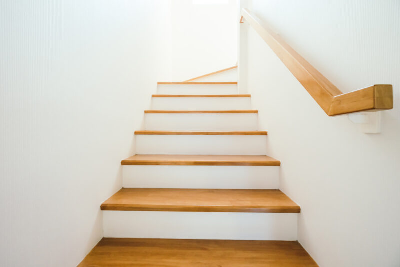 Unutrašnje drvene stepenice sa belim zidovima i rukohvatom